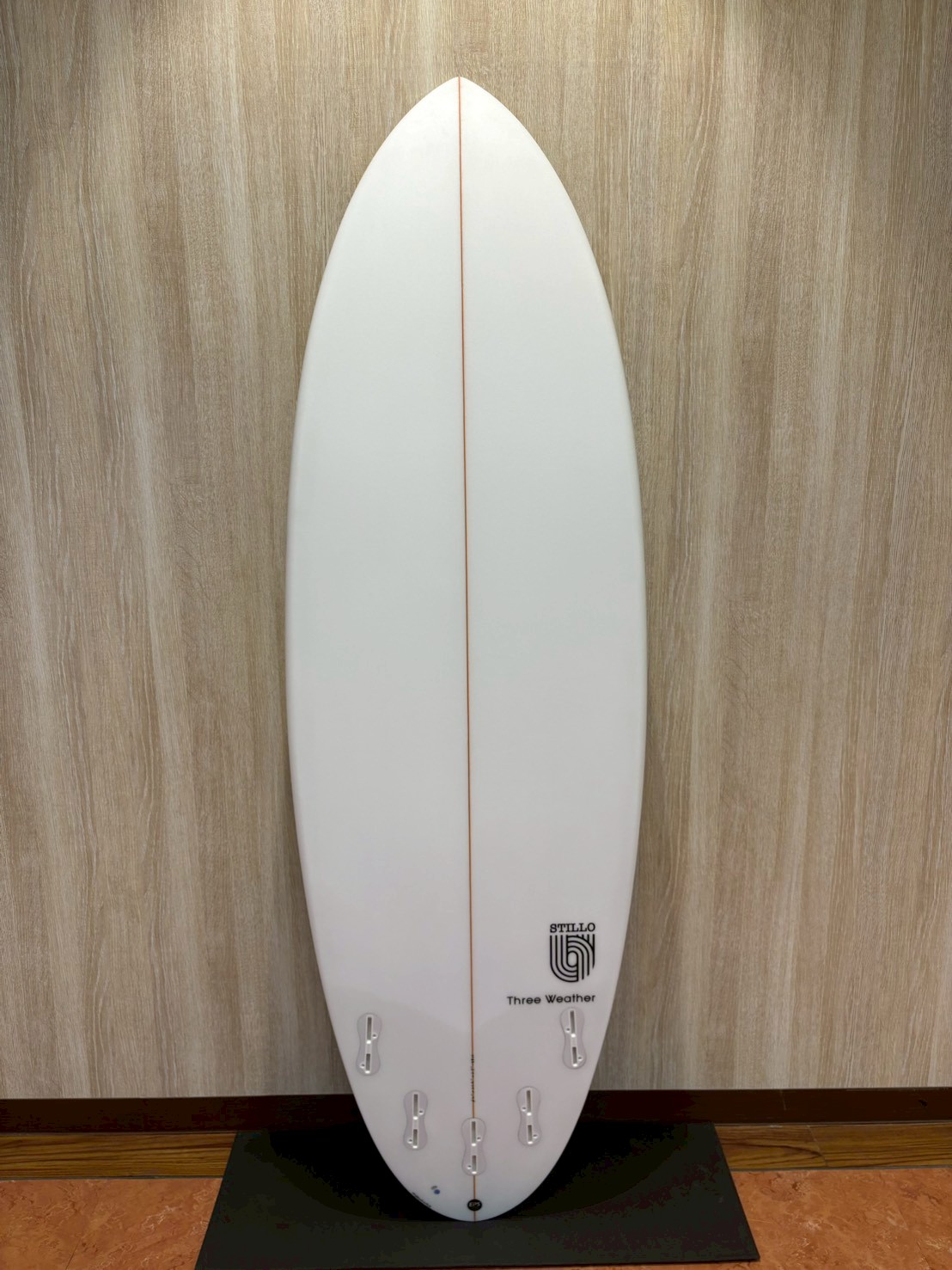LINE_ALBUM_2026 TW_260422_8 - SHOP NEWS | ムラサキスポーツオンラインストア 通販 White surfboard with a thin red center stringer, standing upright against a wooden wall on a display stand.