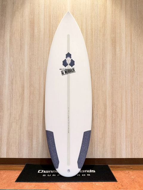s-LINE_ALBUM_2026 CI_260522_1 - SHOP NEWS | ムラサキスポーツオンラインストア 通販 White surfboard standing upright on a black mat indoors, with blue tail pads and an Al Merrick logo center-right.