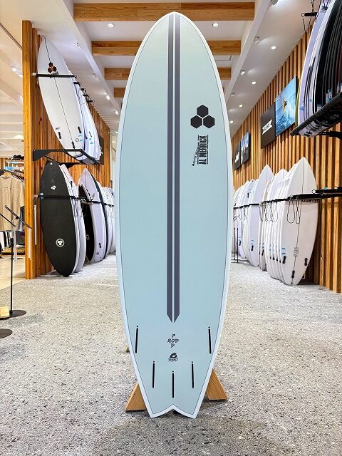Light blue surfboard on a display stand inside a shop, surrounded by other boards and racks.