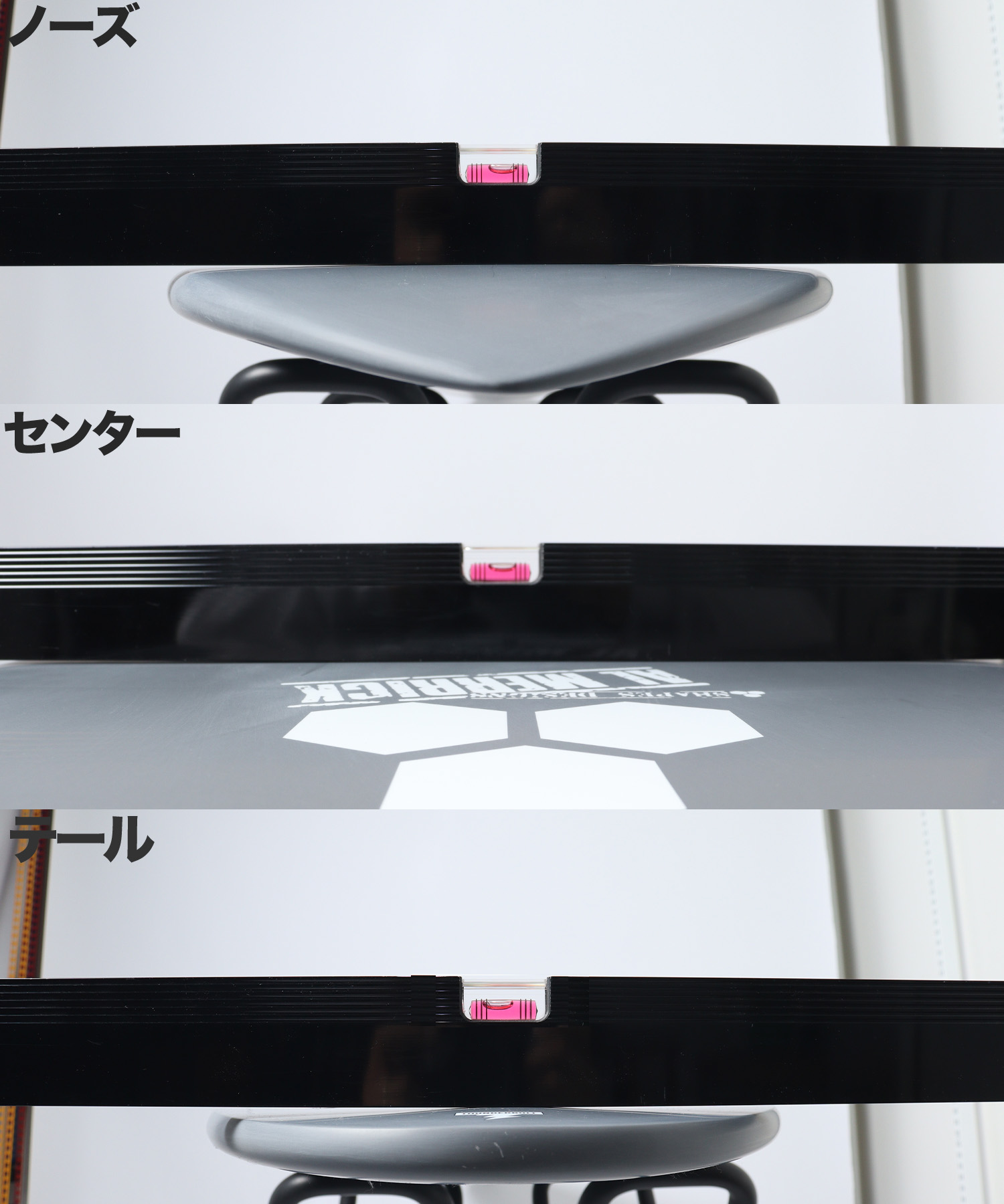 Close-up of a horizontal black bar with a pink spirit level in the center, over a grey curved surface; Japanese labels read nose, center, tail to indicate alignment.