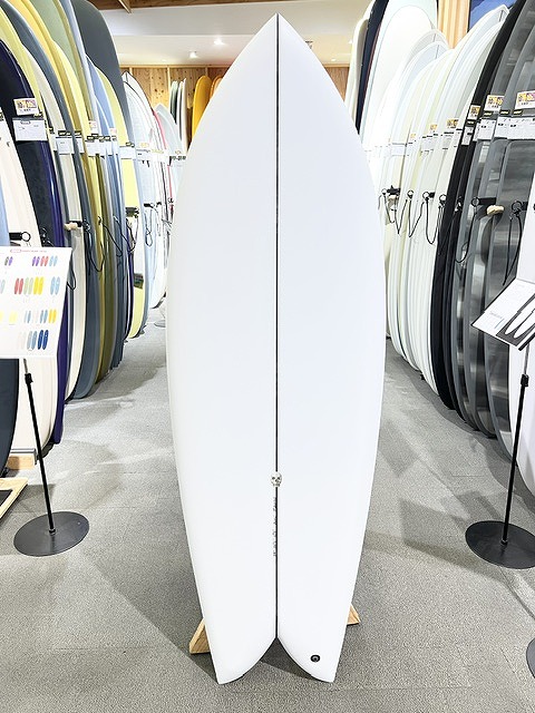 s-IMG_6279 - SHOP NEWS | ムラサキスポーツオンラインストア 通販 White twin-fin surfboard standing upright on display rack in a surf shop showroom.